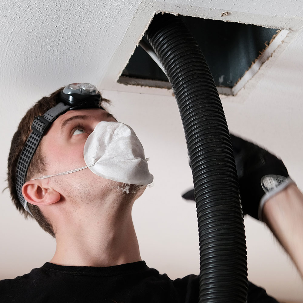 Young man cleaning air duct